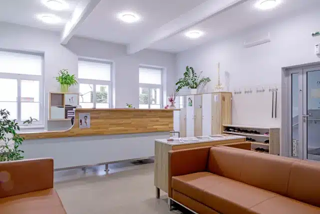 Recepce a čekárna kliniky Eurekofyzio s dřevěným pultem a koženou sedačkou